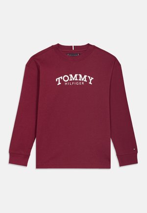 T-shirt à manches longues bordeaux avec col rond, texte blanc "Tommy Hilfiger" sur la poitrine et petit logo sur le bord de la manche droite.