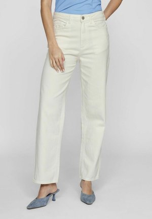 Vaqueros de tiro alto y pierna ancha en denim crema claro, con bolsillos frontales y detalles de costura sutiles, combinados con mules azules.