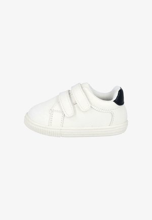 Zapatilla de lona blanca con dos tiras de velcro. Presenta una puntera texturizada y un acento negro en el talón. Suela de goma. Costura lateral visible.