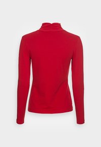 Langärmliges rotes Turtleneck-Oberteil mit figurbetontem Design, weichem Stoff und gerafftem Detail am Hals. Glatte Textur und keine Muster.