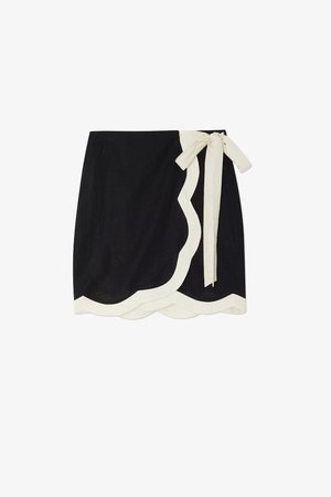 Black wrap skirt with a scalloped cream trim and tie detail. Made from lightweight fabric, featuring a smooth texture and simple design.