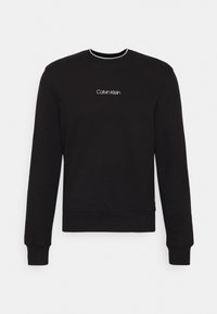 Felpa nera a maniche lunghe con scollatura tonda, con il logo bianco "Calvin Klein" centrato sul petto, polsini e orlo a costine.