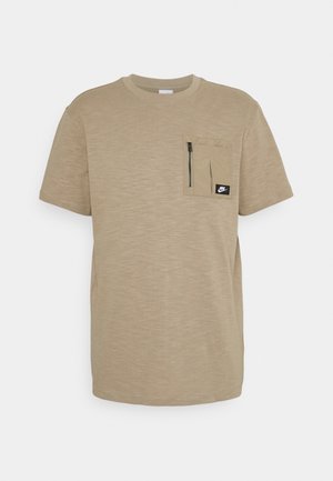 Beżowa koszulka Nike z krótkim rękawem, okrągłym dekoltem i kieszenią na piersi na zamek z naszywką z logo Nike.