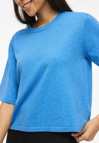 T-shirt en coton bleu avec col rond et manches courtes. Présente une coupe décontractée et une texture douce, se terminant aux hanches par un ourlet droit.
