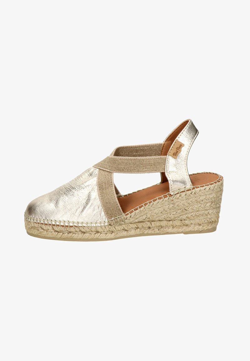 Espadrille compensée en or métallique avec une tige en toile, une sangle élastique croisée et une semelle en jute tissé. Design à dos fermé et bout ouvert.