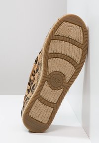 Luipaardprint UGG-slipper met een gestructureerde, tan rubberen zool met een circulair logo en gegroefde patronen voor extra grip.