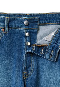 Jeans denim w klasycznym niebieskim kolorze, z metalowymi zapięciami na guziki, pomarańczowym przeszyciem i wewnętrzną paskowaną tkaniną w pasie.