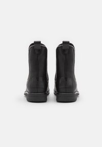 Svarta läderankelboots med en slät yta, dragkedjestängning, tygsömmar och dragflikar bak. Platta, strukturerade gummisulor.