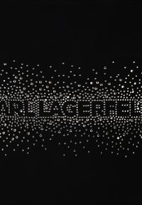 Juodas audinys su išsibarsčiusiais sidabriniais deimantais, sukuriantis gradientinį efektą, o centre didesniais akmenimis yra užrašyta "BRAG".