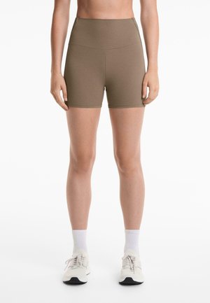 Bruine high-waisted sportshorts van rekbare stof, met een gladde textuur en een aansluitende snit die midden op de bovenbenen eindigt.