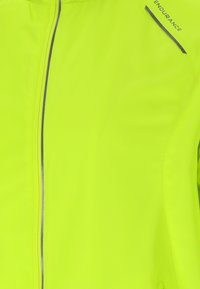 Fluoresenssi keltainen urheilujakku, jossa on tasainen pinta, edessä vetoketju ja pienikokoinen sininen logo olkapäällä.