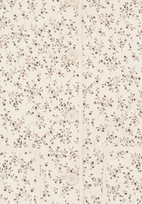 Material crem cu un model delicat de viță de vie florală maro, având patru nasturi albi și două buzunare pătrate cusute.