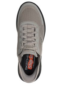 Zapatilla deportiva gris con una parte superior de malla transpirable, puntera reforzada y suela exterior de goma negra. Presenta cordones texturizados y un acolchado en el tobillo.