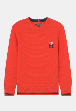 Red knit sweater with crew neck, textured pattern, small Tommy Hilfiger logos on chest and cuff, and navy stripe details on cuffs and hem.
