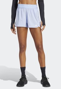 Light blue athletic shorts feature a smooth fabric, elastic waistband with logo accents, and side pockets. Paired with black athletic shoes and socks.