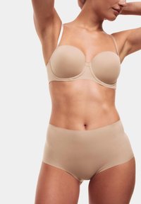 Beige formad behå med tunna justerbara band matchad med högmidjade beige underkläder, båda med en slät, sömlös design.