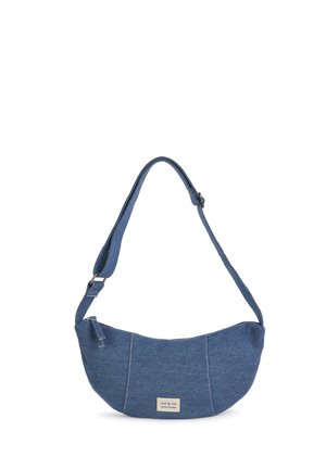 Blue denim shoulder bag with a curved shape, single shoulder strap, and a silver brand tag. Soft texture with visible seams and stitches.