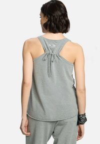 Szary top na ramiączkach wykonany z miękkiego materiału, z wiązanym tyłem i luźnym krojem, w połączeniu z dopasowanymi szarymi dresami.