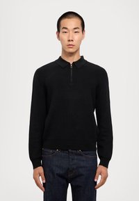 Pullover nero a coste con collo mezzo zip e colletto piatto, caratterizzato da una silhouette aderente e dettagli di texture a contrasto.
