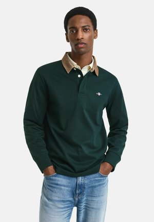 Donkergroene lange mouwen polo met een corduroy kraag. Heeft een drie-knopen sluiting en een geborduurd logo op de borst. Casual fit.