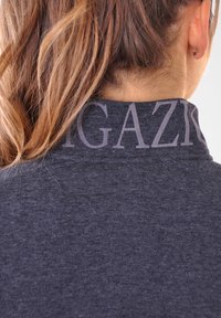 Sweatshirt gris foncé avec un col haut, décoré d'un grand texte subtil au dos. Texture lisse, design décontracté et coupe ajustée.