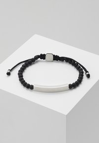 Pulsera de cuentas de piedra de lava negra con un acento de metal plateado rectangular y liso, que cuenta con un cordón ajustable para personalizar el tamaño.