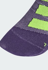 Calcetín morado con un tejido texturizado, que presenta franjas horizontales de un brillante verde y una puntera reforzada. Indicador de tamaño '7' en verde.