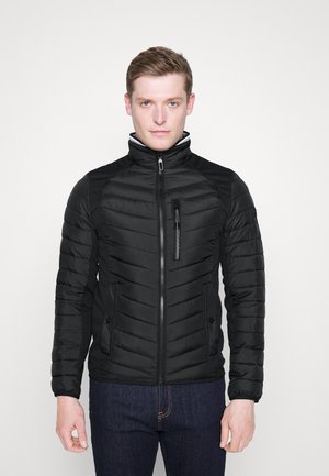 Schwarze Daunenjacke mit hohem Kragen, Reißverschluss vorne und diagonaler Steppung. Mit seitlichen Taschen und einer Brusttasche mit Reißverschluss.