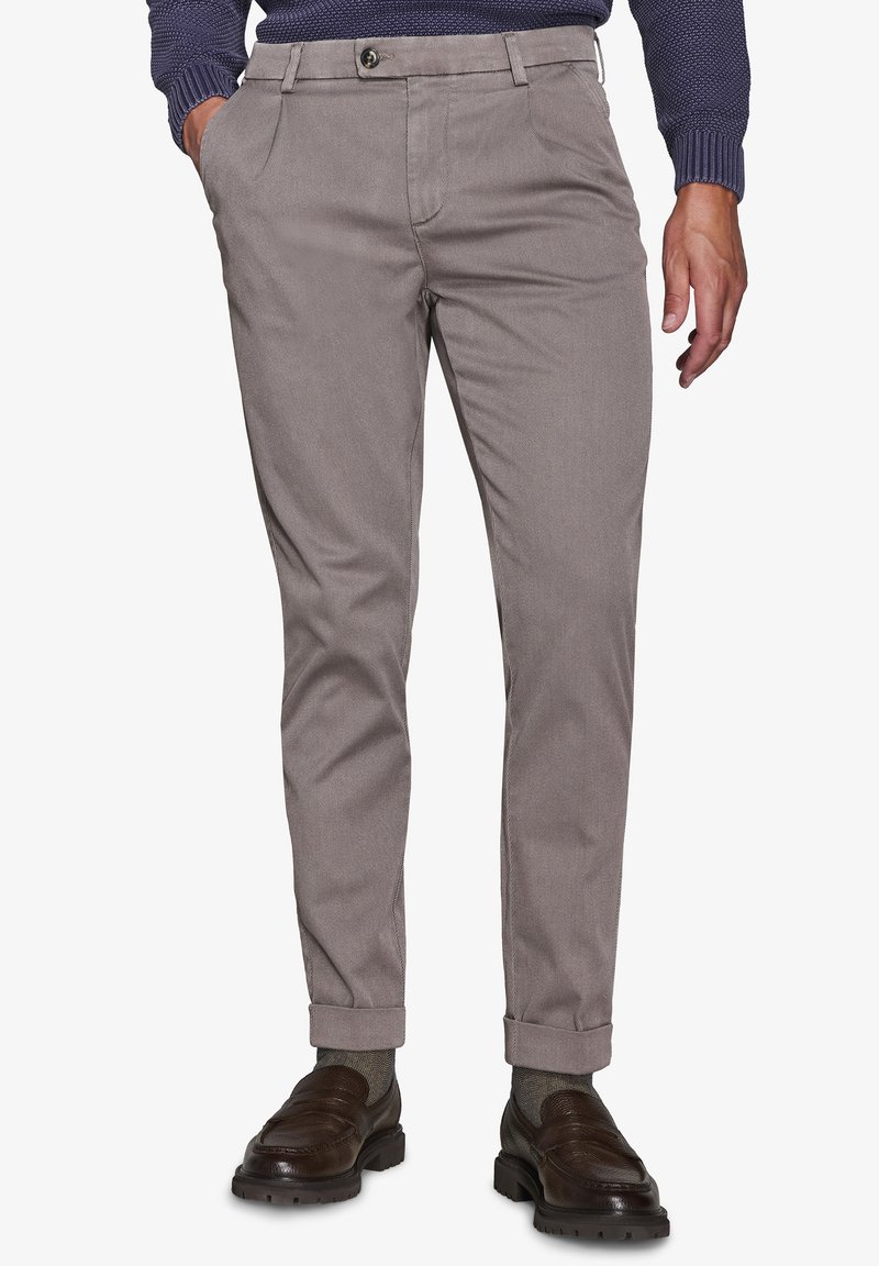 Světle šedé chinos kalhoty vyrobené z texturované tkaniny. Mají slim fit střih, boční kapsy a ohrnuté manžety. V kombinaci s tmavě hnědými mokasínami.