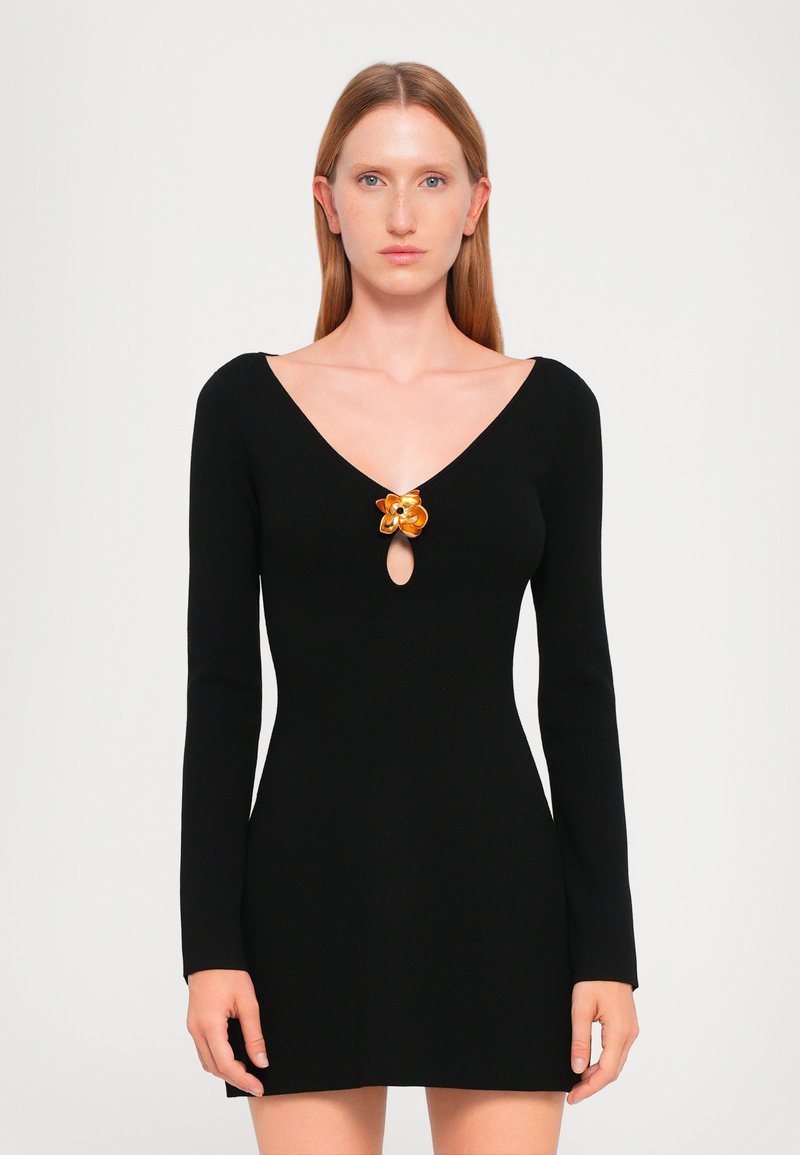 Black knitted dress with a V-neck, long sleeves, and a front keyhole detail. Features a floral accent in orange at the neckline.