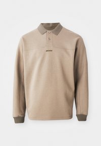 Beige polo shirt made from soft fabric, featuring a ribbed collar and cuffs, two buttons, and a subtle logo on the front.