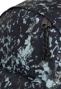 Tessuto a motivo testurizzato nero e verde acqua con un design fogliato. Include una cerniera con due cursori e dettagli intrecciati.