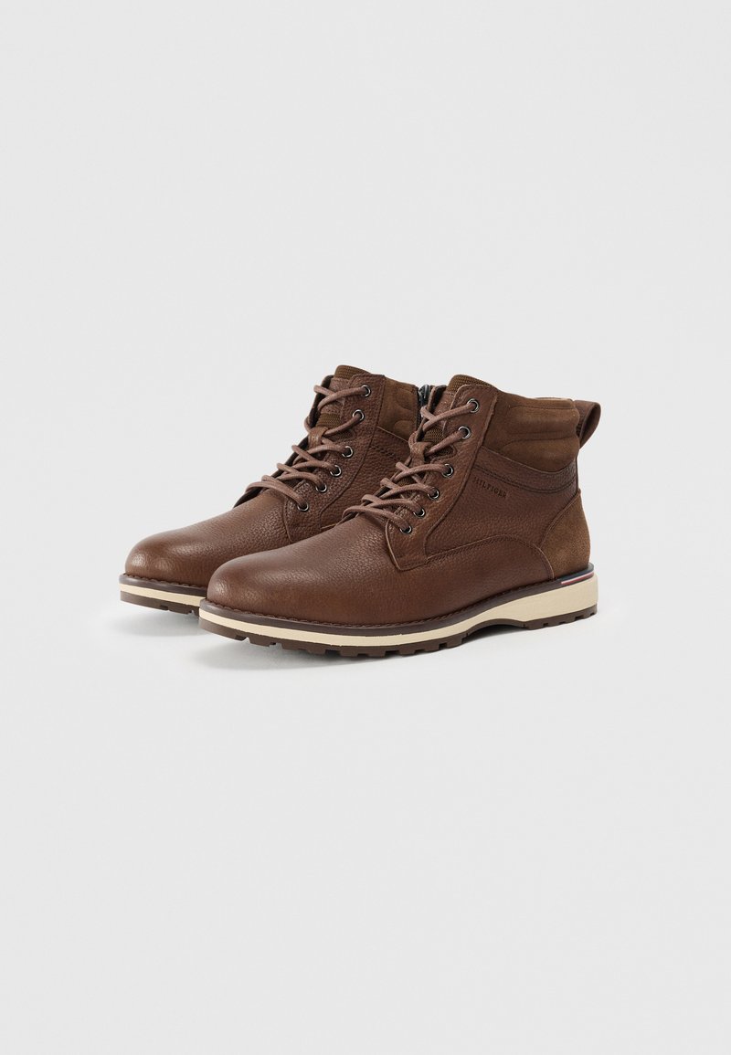 Bottines en cuir marron avec une finition texturée, lacées à l'avant, avec un col rembourré et une semelle en caoutchouc beige contrastante dotée d'un motif de crampons.