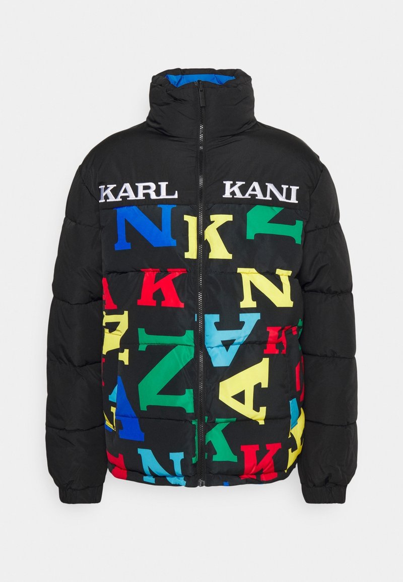 Svart pufferjacka med hög krage, fulla framsidans dragkedja och färgglada överdimensjonerade bokstäver i rött, gult, blått och grönt som stavas "KANI" och "KARL."