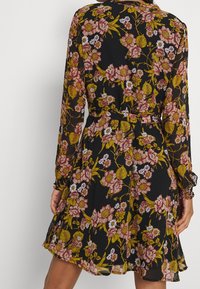 Vestido floral de manga larga, con fondo negro, flores en tonos rosas y amarillos, cintura ceñida y dobladillo acampanado.