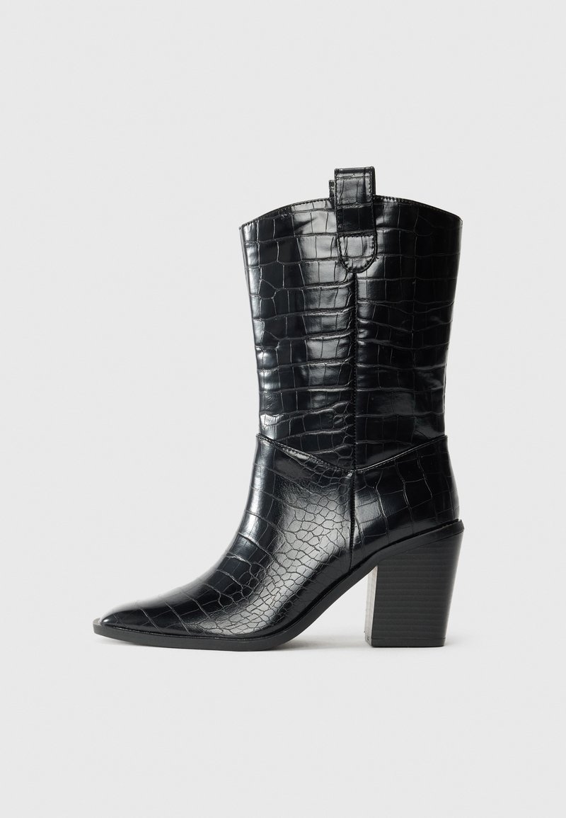 Botte noire mi-mollet à bout pointu avec texture crocodile et talon bloc empilé, languette en haut, vue de côté sur fond clair.