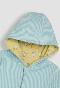 Svijetloplav hooded dukserica sa žutom podstavljanom kapuljačom, koja sadrži uzorak patka i cvjetne detalje. Mekani materijal s vidljivim šavovima.