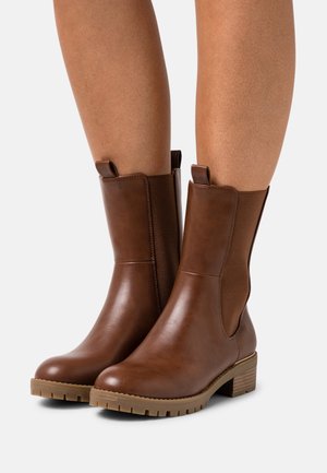 Bruna läderankelstövlar med elastiska sidopaneler, rundad tå, texturerad sula och en klack i staplad design. Ovandelen är slät med en glänsande yta.