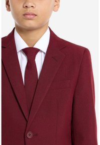 Chaqueta de traje burdeos con un acabado texturizado, solapa con muesca, cierre de un solo botón y una corbata a juego sobre una camisa de vestir blanca.