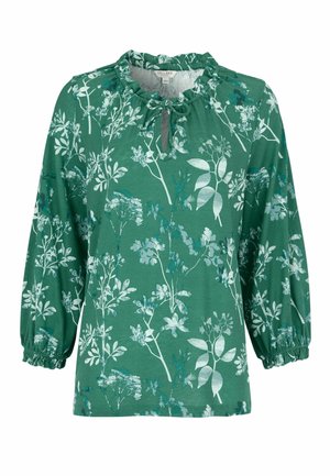 Grøn bluse med lange ærmer med hvide og blå blomsterprint, elastiske manchetter og en flæsekrave med en bindedetalje foran.