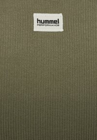Olivengroene geribbelde stof met een gestikt wit etiket met "hummel PERFORMANCE" in zwarte tekst. Minimalistisch ontwerp, gladde textuur.