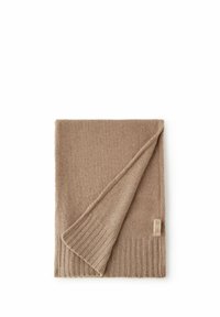 Beżowy wełniany szal o gładkiej fakturze i prążkowanym brzegu. Jeden róg jest złożony, odsłaniając metkę z informacją o marce.
