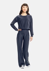 Dark gray athletic outfit featuring a relaxed long-sleeve top and wide-leg pants with a high waistband. Material: soft, smooth texture.