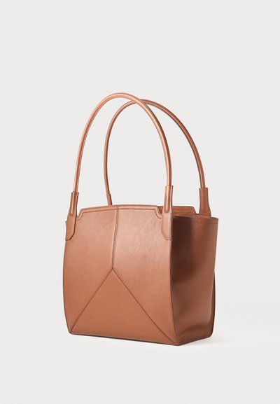 Sac cabas en cuir marron avec doubles poignées arrondies et détail de couture géométrique sur le devant, sur un fond clair uni.