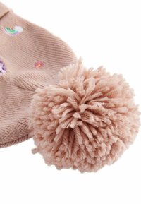 Ljusrosa virkade mössa med färgglada broderade motiv och en stor, fluffig pom-pom på toppen, vilket betonar en mjuk textur.