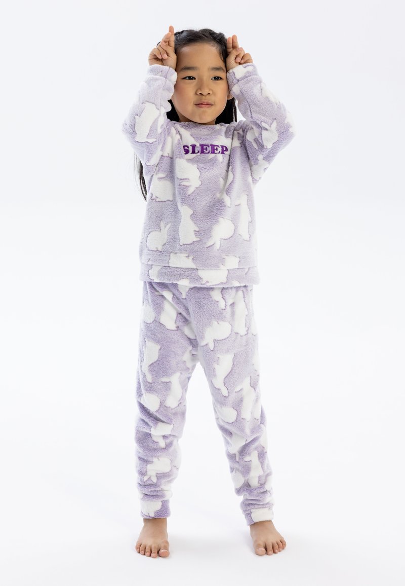 Lila fluffig pyjamaset med vita kaninsilhuetter och texten "SLEEP" i lila på toppen; mjukt material med elastiska manschetter och midjeband.