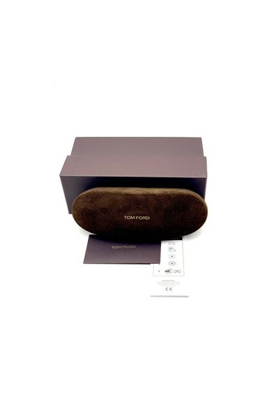 Étui à lunettes en suede marron de forme ovale avec le logo doré "TOM FORD". Accompagné d'une boîte violet foncé et d'une carte d'instructions d'entretien.