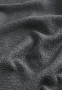 Tejido de punto gris con una textura fina, mostrando suaves pliegues y una superficie lisa, destacando su diseño versátil y la calidad del material.