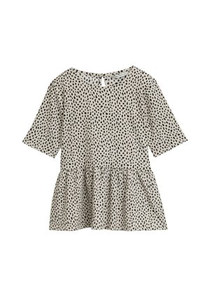 Top peplum a maniche corte in beige chiaro con pois neri irregolari, caratterizzato da un colletto rotondo e un dettaglio a chiave sulla schiena.