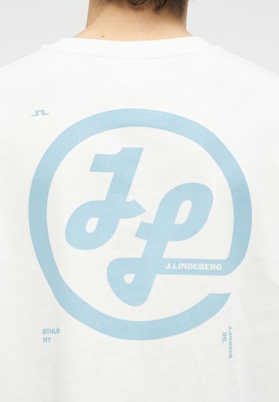 Λευκό πίσω μέρος πουκάμισου με μεγάλο λογότυπο "JL" σε ανοιχτό μπλε και το κείμενο "J. Lindeberg" εκτυπωμένα στο κέντρο.